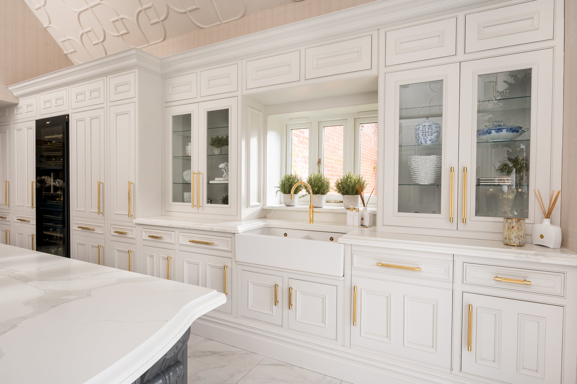Luxurious bedroom with white cabinets, gold handles, and decorative elements.