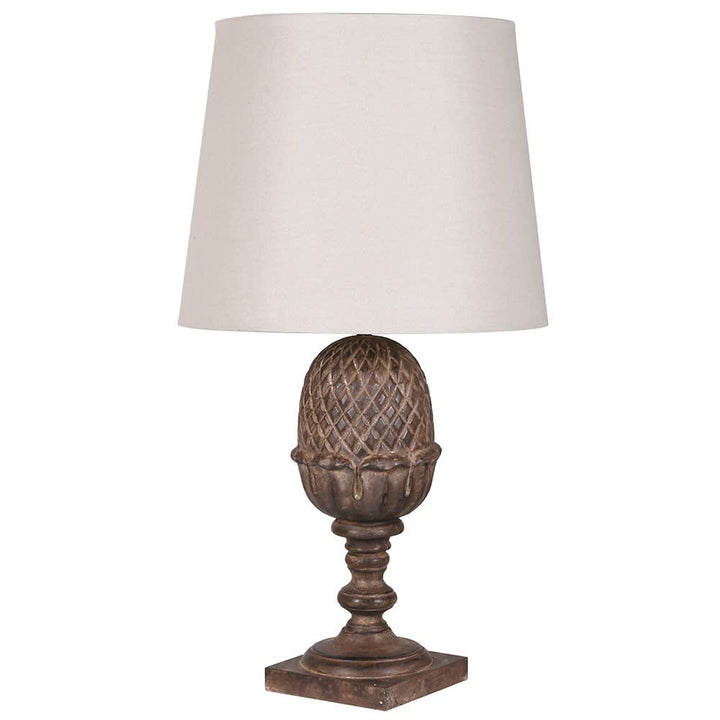 A table lamp with a textured, dark brown pinecone-shaped metal base and a tapered off-white fabric drum shade, shown against a plain white background.