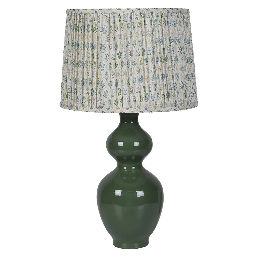 A table lamp with a glossy dark green ceramic gourd-shaped base and a pleated drum shade featuring a blue and green floral pattern on a cream background, set against a plain white background.