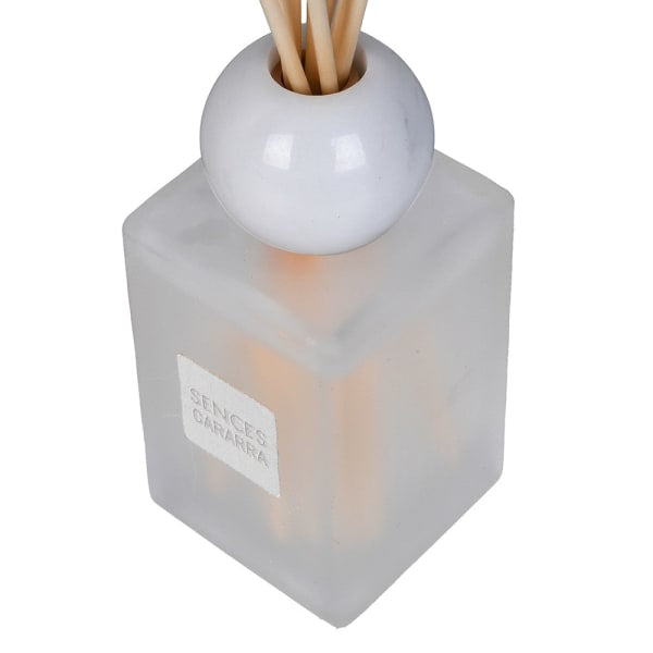 A reed diffuser bottle with a frosted translucent square glass body, a glossy white spherical top, and natural wood reeds, with a white label reading &