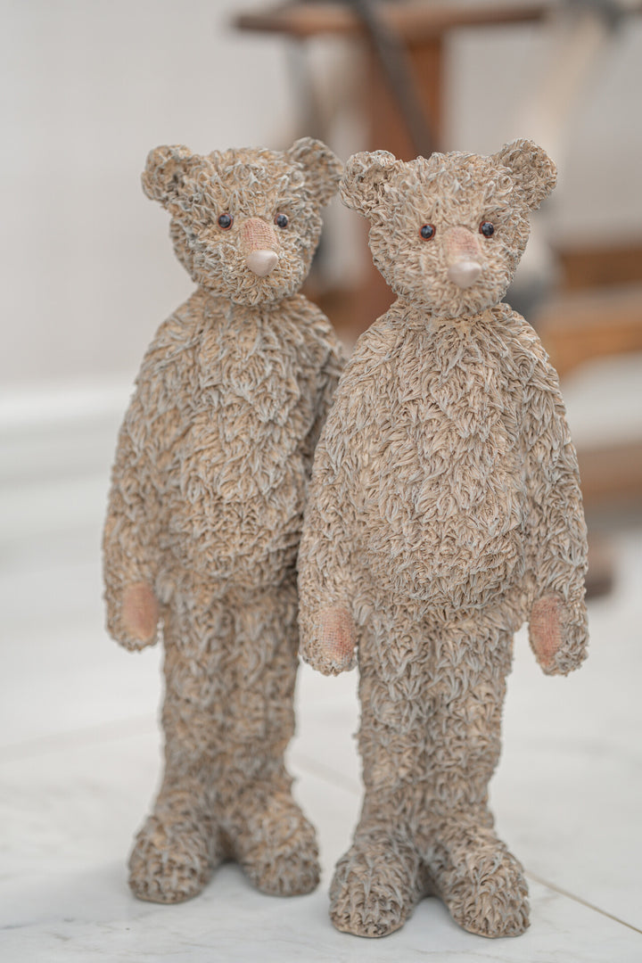 Two plush teddy bears standing side by side on a light surface.