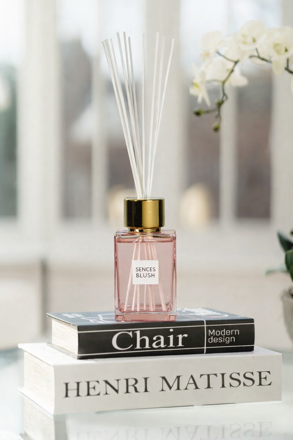 Pink diffuser bottle labeled 'Senses Blush' on top of books with a blurred indoor background