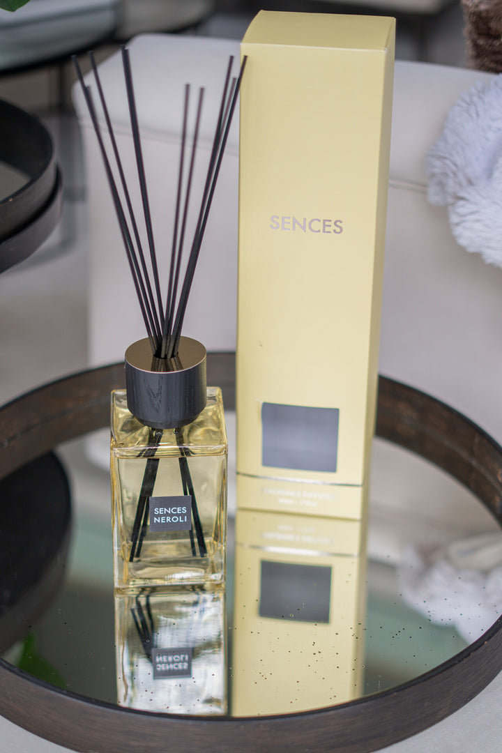 Reed diffuser with packaging on a reflective surface