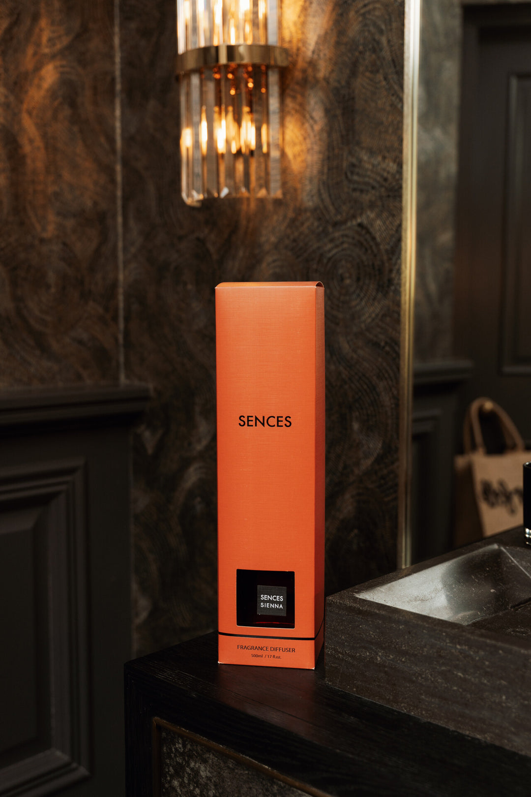Orange box with 'SENCES' branding on a dark countertop against a textured wall.