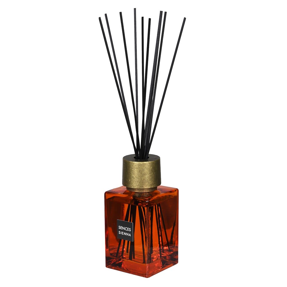 Diffuser with black sticks and gold cap on a white background