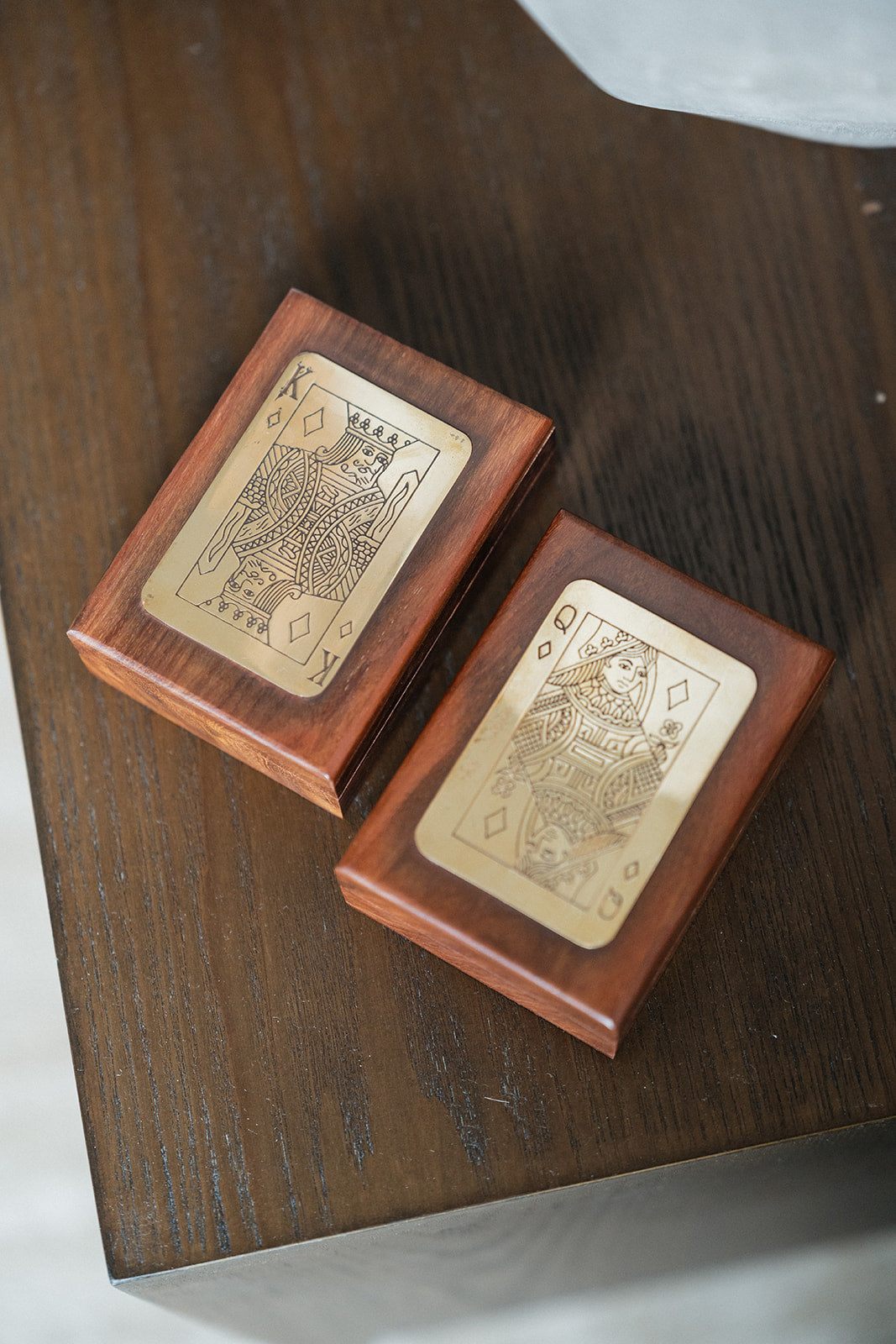 Two wooden keepsake boxes with engraved playing card designs, displayed on a dark wooden table.