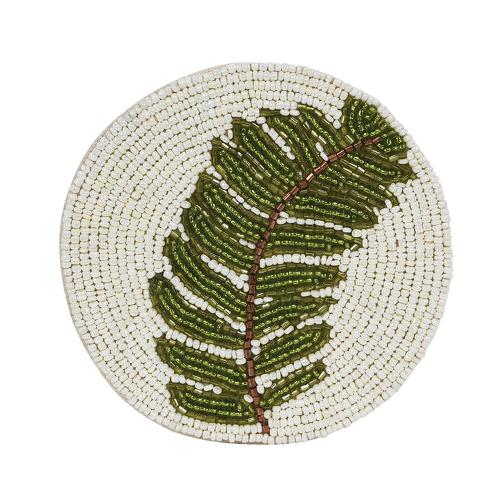 A round woven placemat featuring a large green fern leaf design on a cream-colored woven background, isolated on a white background.