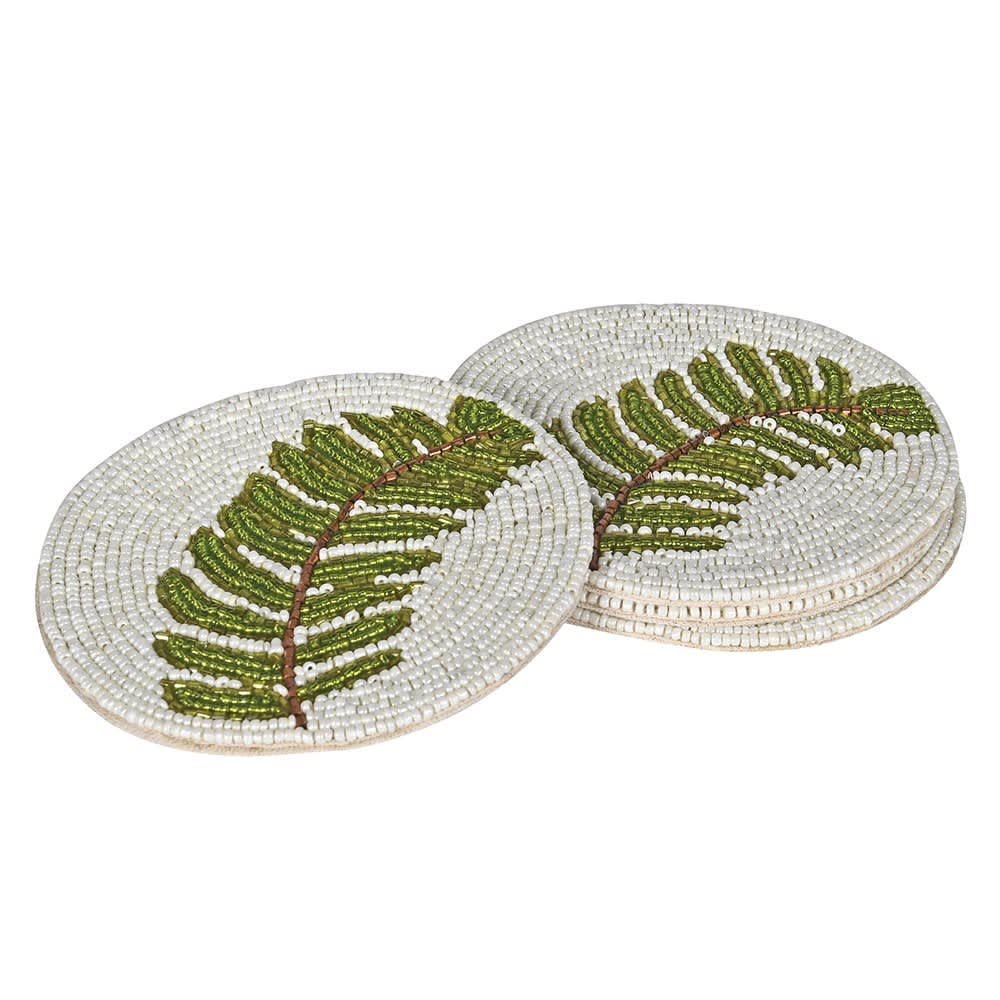 Two round woven coasters with a green fern leaf design on a white background, shown on a plain white studio background.