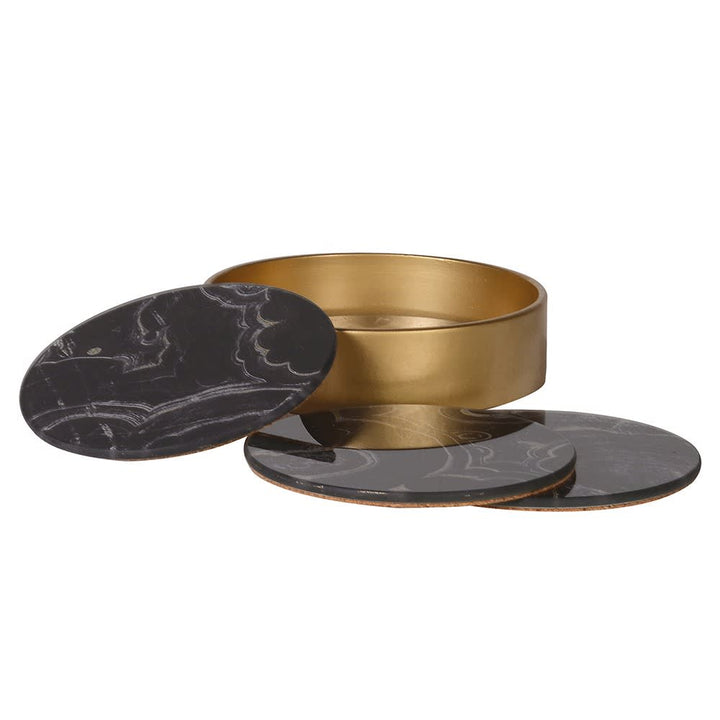 A round gold metal tin container with a matching oval black marble-patterned lid, shown alongside two coasters on a plain white background.