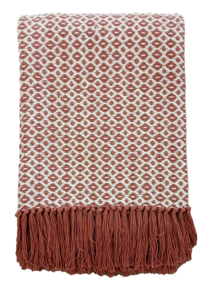 A folded woven throw blanket with a rust-brown and off-white geometric diamond pattern and a matching fringed edge, shown on a plain white background.