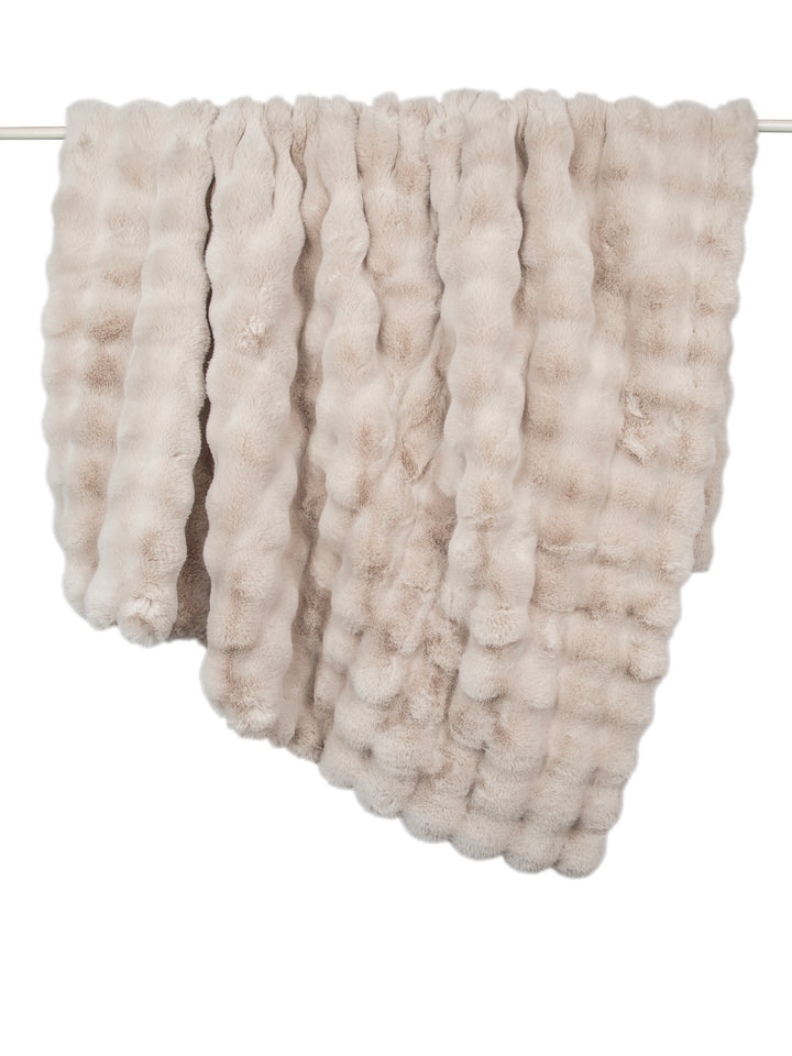 Textured beige blanket draped over a rack on a white background
