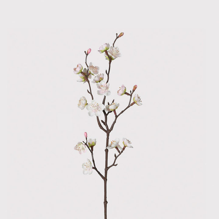 A single artificial flowering branch with white blossoms and pink buds on a brown stem, photographed against a plain light gray background.