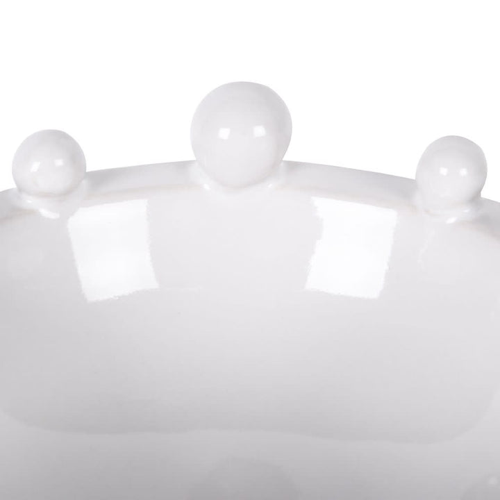 Close-up of a white crown with three spherical ornaments on a white background